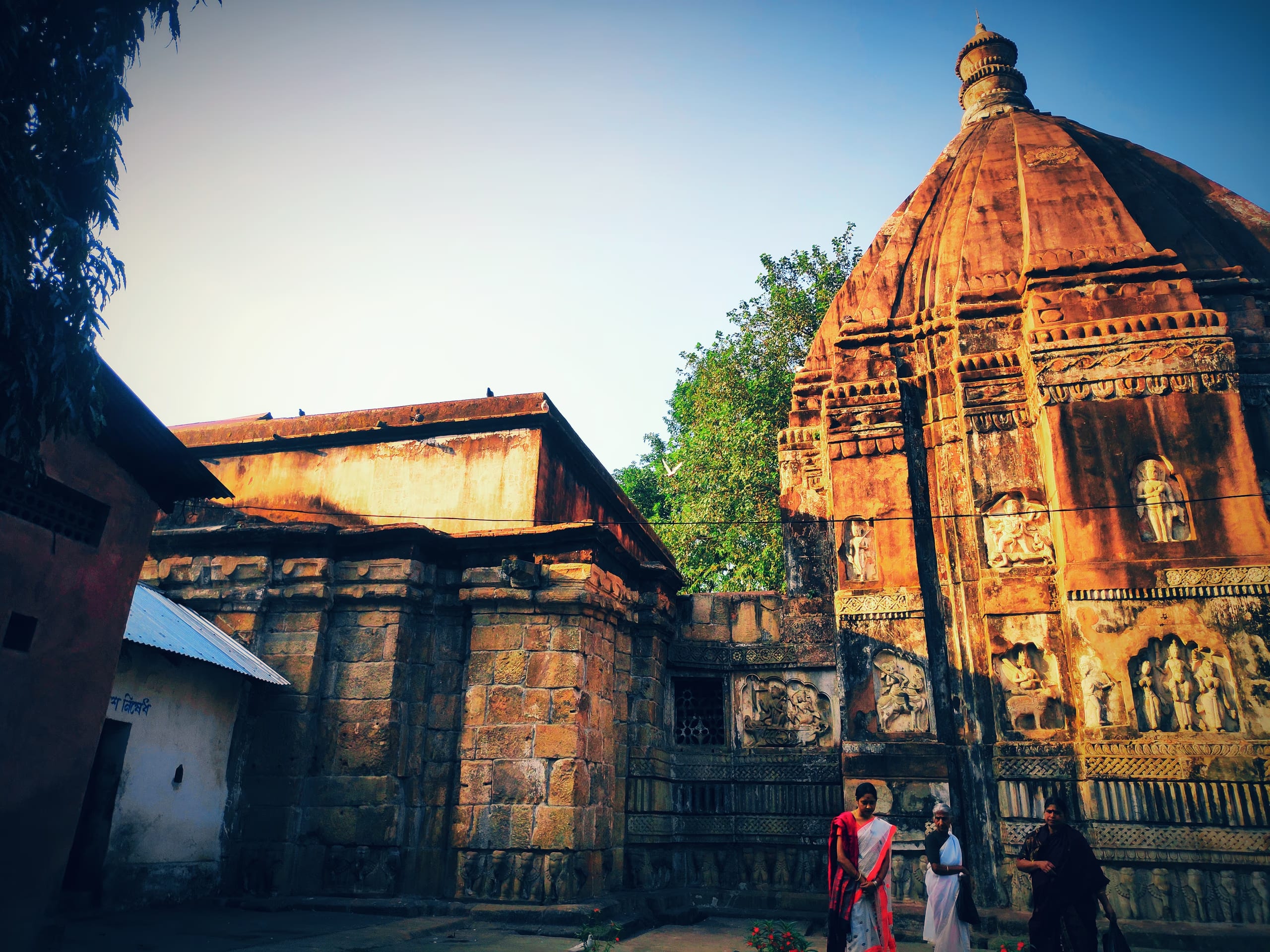 The stone Hayagriva Madhava temple at Hajo, its curved tower carved with relief panels beside the adjoining hall