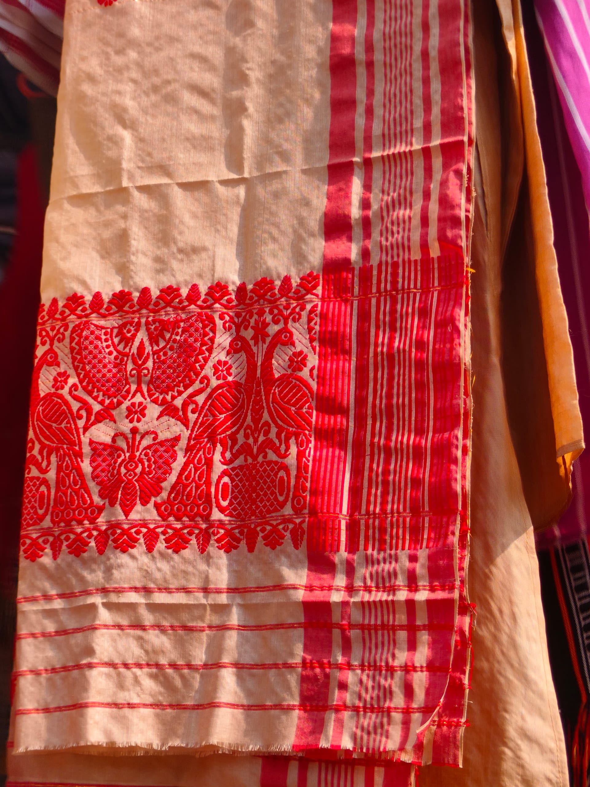 Cream cotton gamosa with a woven red floral and peacock motif and a red-striped border