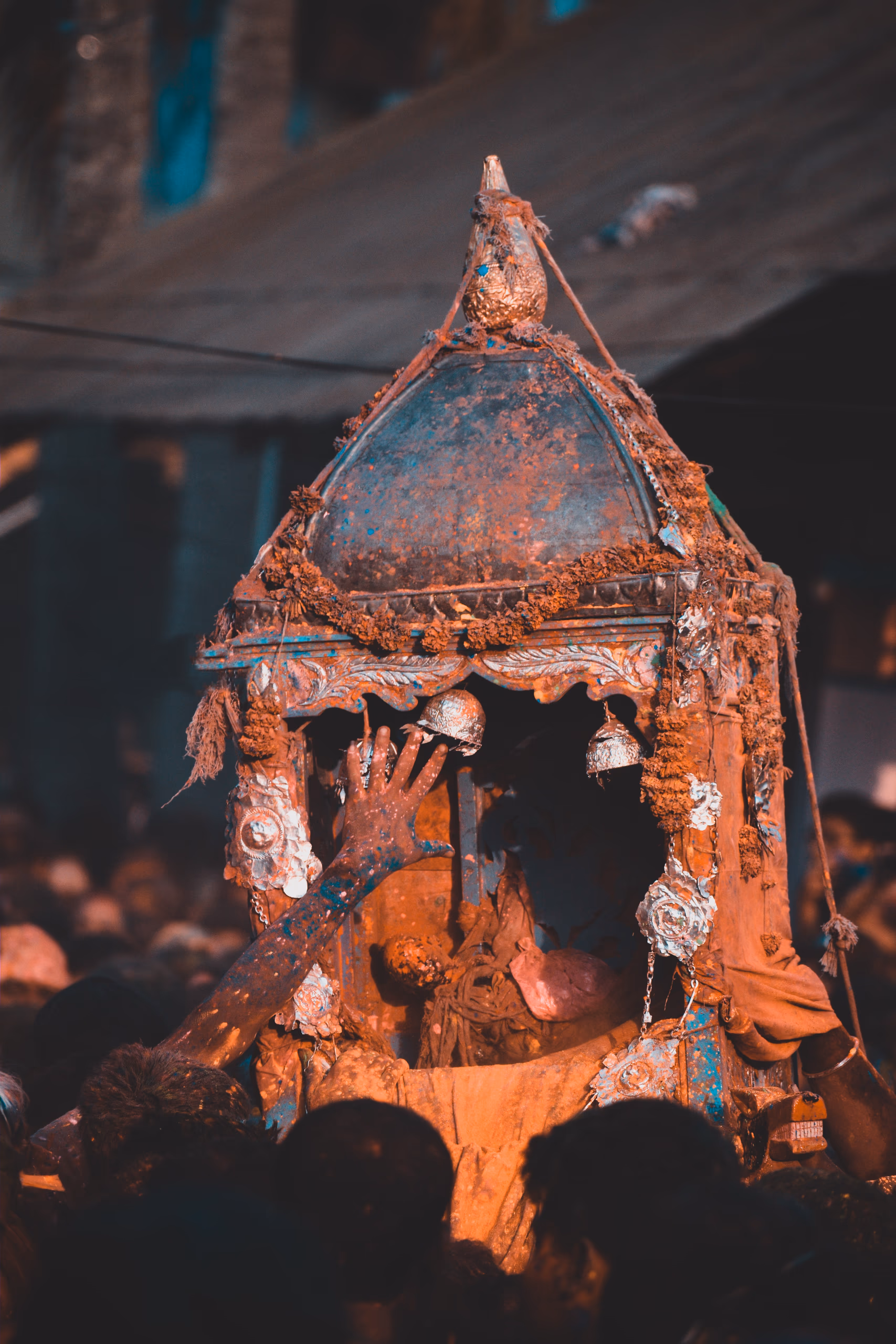 A gulal-smeared palanquin carried above a crowd during the Doul festival at Barpeta
